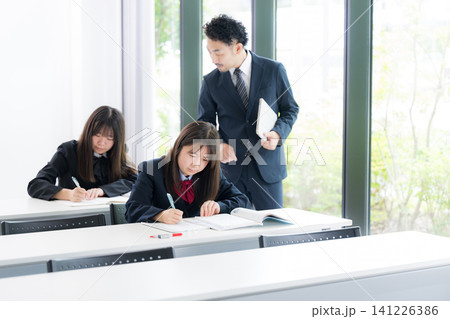 塾や学校の教室で個別指導を行う教師と勉強に取り組む日本人女子中学生や女子高校生イメージ 個別や集団塾 塾や学校の教室で個別指導を行う教師と勉強に取り組む日本人女子中学生や女子高校生イメージ 個別や集団塾 141226386
