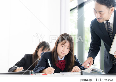 塾や学校の教室で個別指導を行う教師と勉強に取り組む日本人女子中学生や女子高校生 塾や学校の教室で個別指導を行う教師と勉強に取り組む日本人女子中学生や女子高校生 141226398