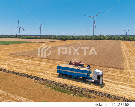 Modern farming equipment collecting wheat crop with wind power generators 141226680
