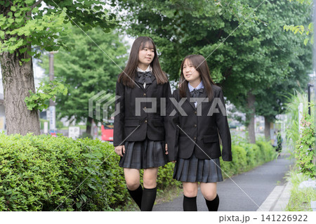 屋外の緑背景で会話する歩く笑顔で寄り添う日本人女子高校生　二人で過ごす高校生活と青春 141226922