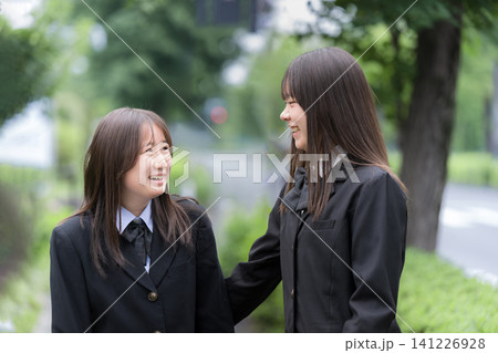 屋外の緑背景で会話する歩く笑顔で寄り添う日本人女子高校生 二人で過ごす高校生活と青春 屋外の緑背景で会話する歩く笑顔で寄り添う日本人女子高校生 二人で過ごす高校生活と青春 141226928