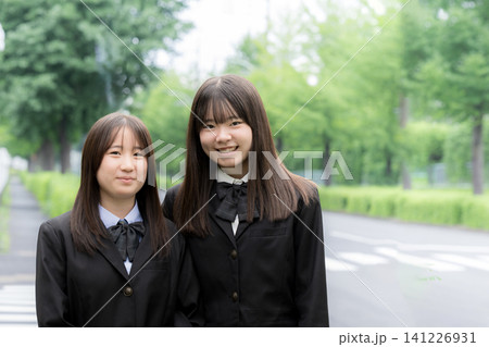 屋外の緑背景で笑顔で寄り添う日本人女子高校生 二人で過ごす高校生活と青春 カメラ目線笑顔 屋外の緑背景で笑顔で寄り添う日本人女子高校生 二人で過ごす高校生活と青春 カメラ目線笑顔 141226931
