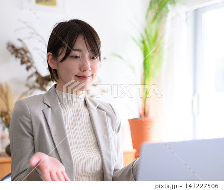 ノートパソコンを見ながら話す女性 ノートパソコンを見ながら話す女性 141227506