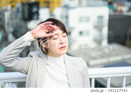 暑さで額に手を当てる女性 暑さで額に手を当てる女性 141227541