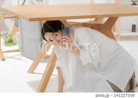 机の下に逃げる女性 141227556