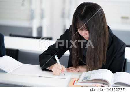 教室で真剣に勉強へ取り組む日本人女子高校生　受験や定期テストに向けて自習する学生 141227774
