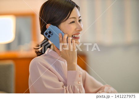 夜部屋でリラックスしてスマホを見る40代の女性 141227975