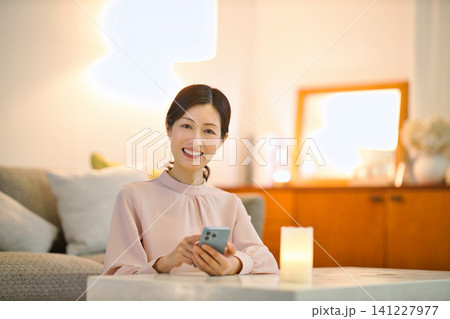 夜部屋でリラックスしてスマホを見る40代の女性 夜部屋でリラックスしてスマホを見る40代の女性 141227977