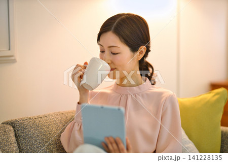 夜部屋でリラックスしてタブレットを見る40代の女性 夜部屋でリラックスしてタブレットを見る40代の女性 141228135