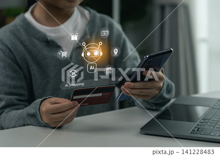 Person using smartphone and credit card for artificial intelligence powered online shopping with digital icons hologram ai interface over hands technology and laptop on table 141228483