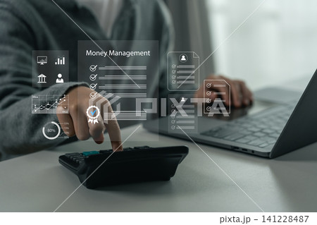 Person using calculator for financial calculation with transparent digital interface icons displaying money management concepts and data analytics on desk with laptop computer Person using calculator for financial calculation with transparent digital interface icons displaying money management concepts and data analytics on desk with laptop computer 141228487