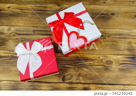 Gift boxes and red heart on a wooden background. Valentine's Day concept Gift boxes and red heart on a wooden background. Valentine's Day concept 141230242