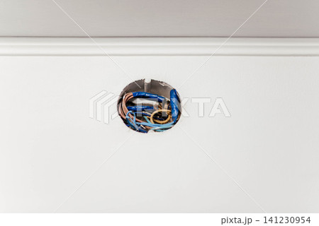 Close-up of an open electrical junction box with exposed wiring inside a white wall during home renovation. Electrical installation, residential construction, wiring maintenance, repair and safety Close-up of an open electrical junction box with exposed wiring inside a white wall during home renovation. Electrical installation, residential construction, wiring maintenance, repair and safety 141230954