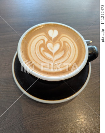 Close Up of an Oat Milk Latte Coffee in White Cup on a Wooden Table Background with Milk Art Close Up of an Oat Milk Latte Coffee in White Cup on a Wooden Table Background with Milk Art 141232472
