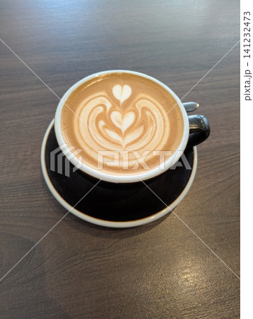 Close Up of an Oat Milk Latte Coffee in White Cup on a Wooden Table Background with Milk Art Close Up of an Oat Milk Latte Coffee in White Cup on a Wooden Table Background with Milk Art 141232473
