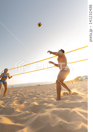 People playing beach volleyball on sand at sunset 141232486