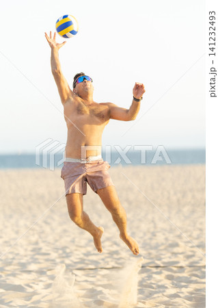 Male athlete jumping, spiking volleyball on beach Male athlete jumping, spiking volleyball on beach 141232493