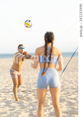 Man and woman playing beach volleyball on a sunny day Man and woman playing beach volleyball on a sunny day 141232499