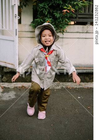 Cheerful young Asian girl in scout uniform with hat and scarf Cheerful young Asian girl in scout uniform with hat and scarf 141232862
