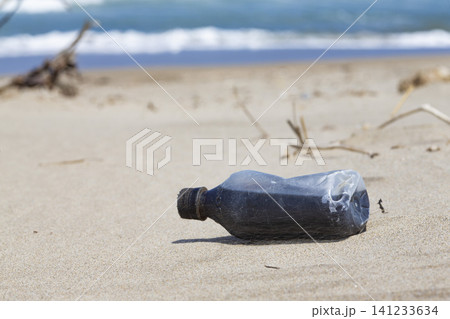 砂浜に打ち上げられた潰れたプラスチック容器 141233634