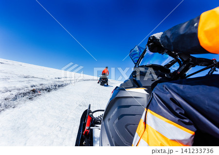 First-person view of a snowmobile tour across a vast Icelandic glacier. Adventure travel through pristine snowfields beneath a dramatic blue sky with wispy clouds in Iceland. First-person view of a snowmobile tour across a vast Icelandic glacier. Adventure travel through pristine snowfields beneath a dramatic blue sky with wispy clouds in Iceland. 141233736