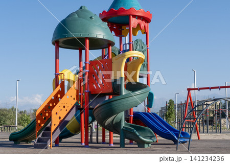 Colorful children playground equipment with slides and towers outdoors Colorful children playground equipment with slides and towers outdoors 141234236