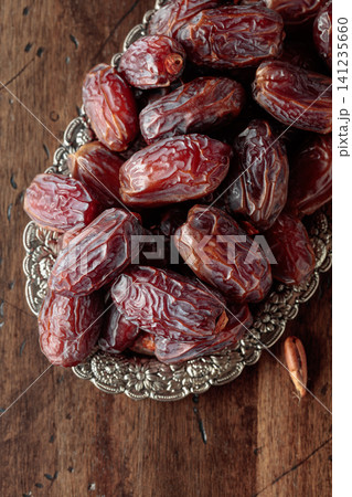 Dried dates fruit in silver tray on a wooden table. Dried dates fruit in silver tray on a wooden table. 141235660