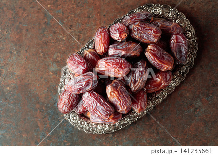 Dried dates fruit in silver tray on a rustic background. Dried dates fruit in silver tray on a rustic background. 141235661