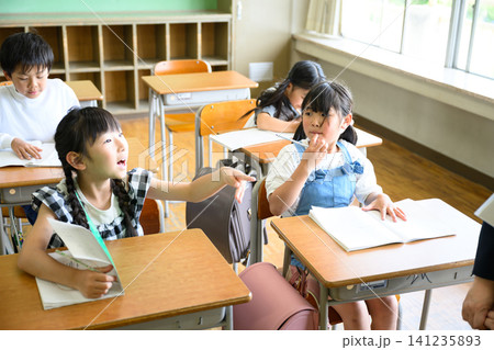 教室の机で集中して勉強し、できたと得意げな表情をする小学生たち 教室の机で集中して勉強し、できたと得意げな表情をする小学生たち 141235893