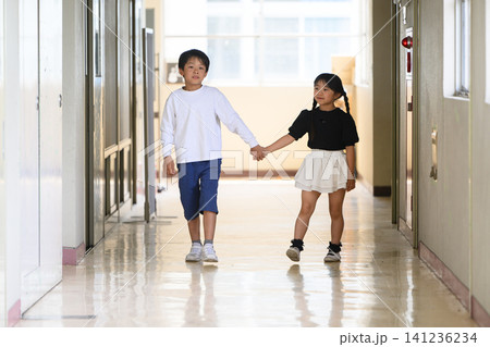学校の廊下を手をつないで歩いてくる男女の小学生 学校の廊下を手をつないで歩いてくる男女の小学生 141236234
