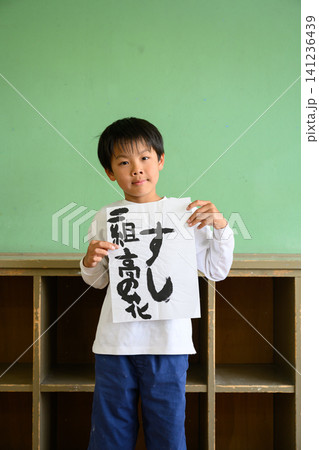 教室で自慢気に「すし」と書かれた習字の作品を見せる男子小学生 教室で自慢気に「すし」と書かれた習字の作品を見せる男子小学生 141236439