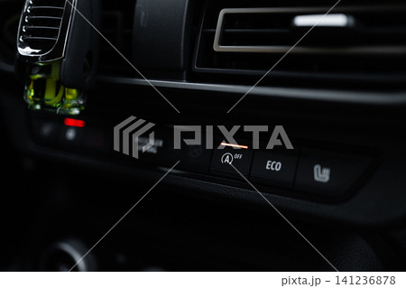 Illuminated ECO mode button on modern car central console in darkness. Illuminated ECO mode button on modern car central console in darkness. 141236878