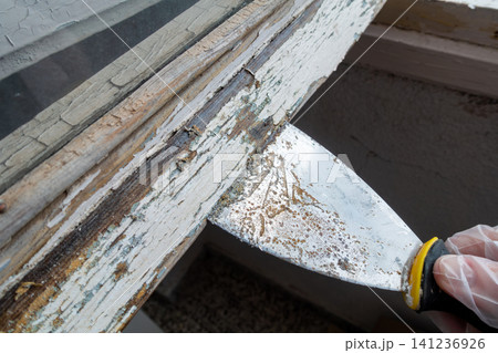 Removing Old Paint from Wooden Window Frame with Putty Knife 141236926