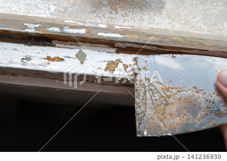 Removing Old Paint from Wooden Window Frame with Putty Knife 141236930