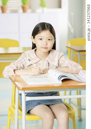 Smiling elementary student studying at a classroom desk Smiling elementary student studying at a classroom desk 141237068