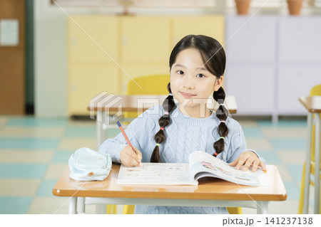 Young schoolgirl raising her hand while studying in class Young schoolgirl raising her hand while studying in class 141237138