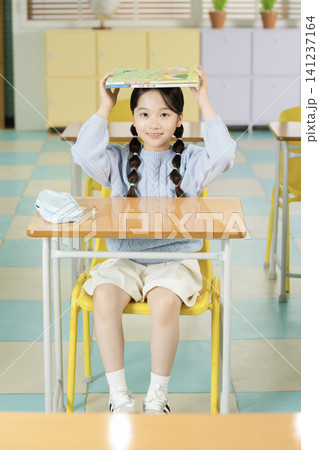 Schoolgirl with backpack smiling in a bright classroom Schoolgirl with backpack smiling in a bright classroom 141237164