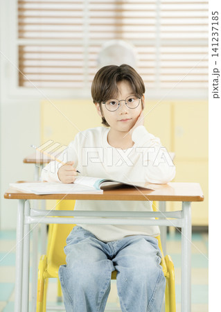 Asian elementary schoolboy with glasses studying in a classroom Asian elementary schoolboy with glasses studying in a classroom 141237185
