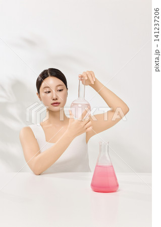Woman examining cosmetic ingredients in flasks for a skincare concept 141237206