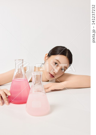 Young Asian woman holding an amber skincare serum bottle Young Asian woman holding an amber skincare serum bottle 141237232