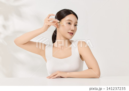Asian woman smiling with an amber beauty product bottle Asian woman smiling with an amber beauty product bottle 141237235