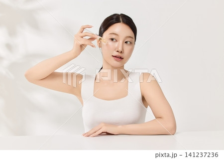 Young Asian woman holding an amber skincare serum bottle Young Asian woman holding an amber skincare serum bottle 141237236