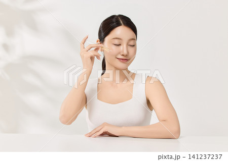 Beauty model posing with a brown cosmetic bottle in a clean studio Beauty model posing with a brown cosmetic bottle in a clean studio 141237237