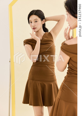 Young Asian woman checking her outfit in a full-length mirror Young Asian woman checking her outfit in a full-length mirror 141237460
