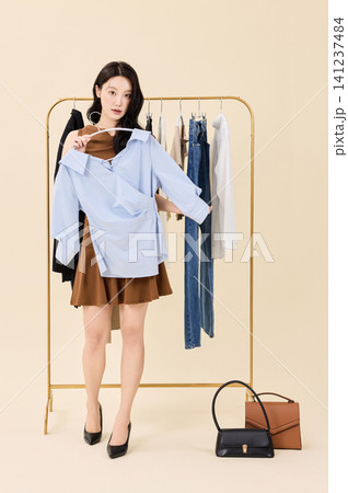 Fashion model selecting outfits on a clothing rack Fashion model selecting outfits on a clothing rack 141237484