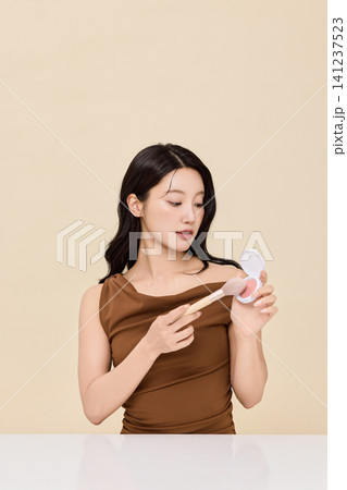 Woman checking her lips in a round handheld mirror Woman checking her lips in a round handheld mirror 141237523