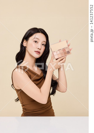 Asian woman presenting cosmetic palette during a makeup routine Asian woman presenting cosmetic palette during a makeup routine 141237552