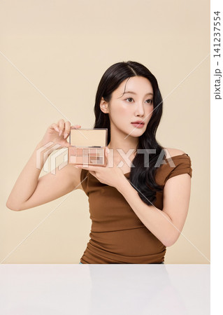 Woman checking her lips in a round handheld mirror 141237554