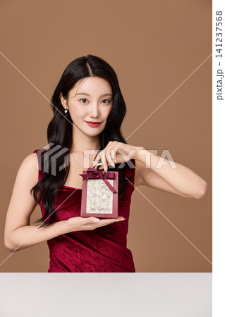 Holiday gift presentation with an elegant woman in a red dress 141237568