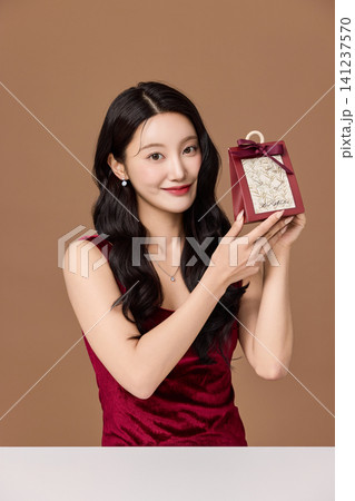 Elegant Asian woman presenting a wrapped gift box 141237570
